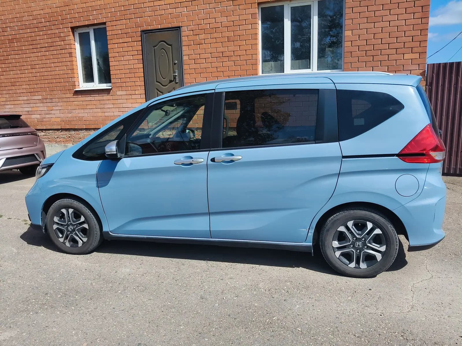 Honda Freed у кирпичного здания на площадке приёмки, левый борт